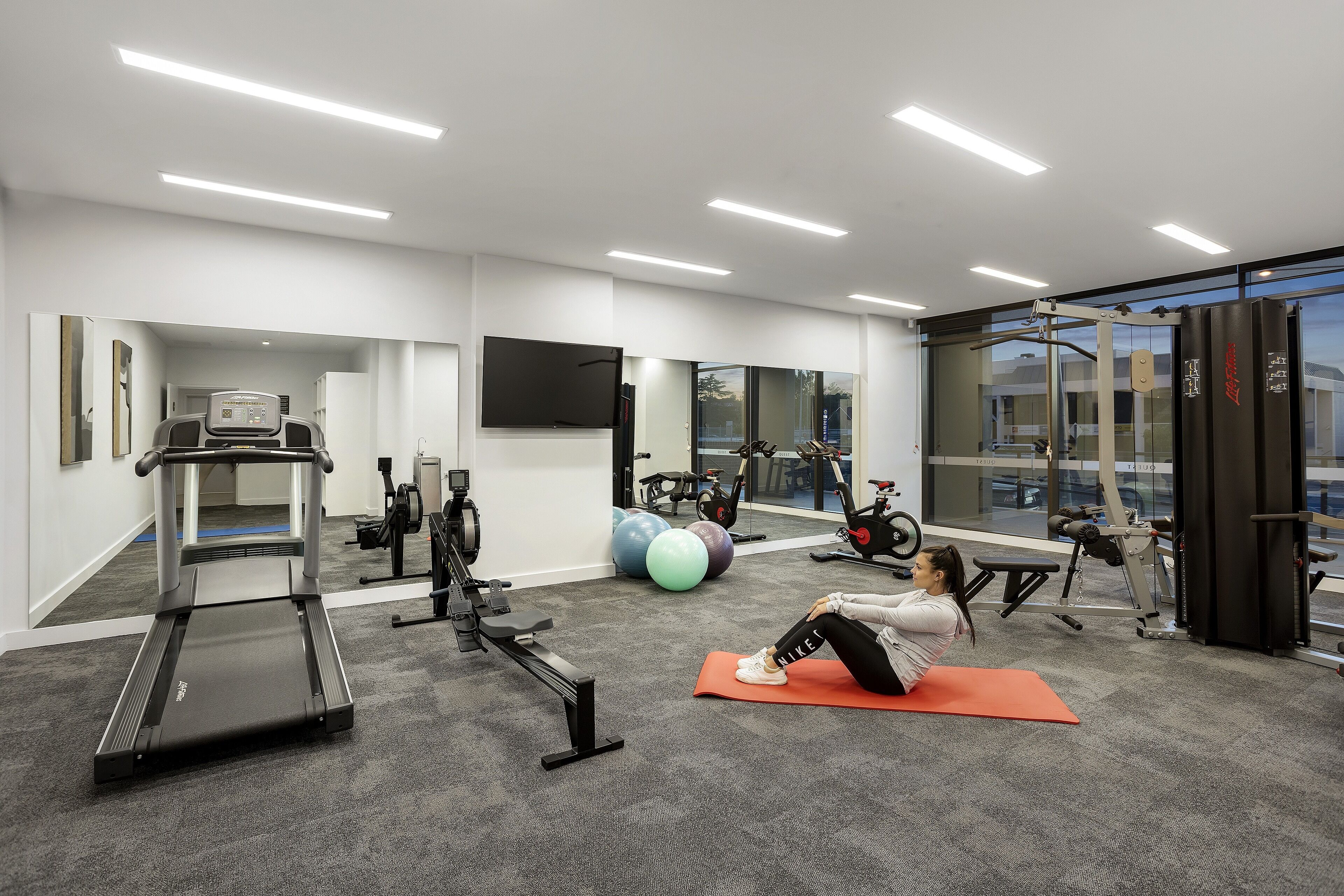 A gym with treadmills, exercise balls, and a rowing machine.