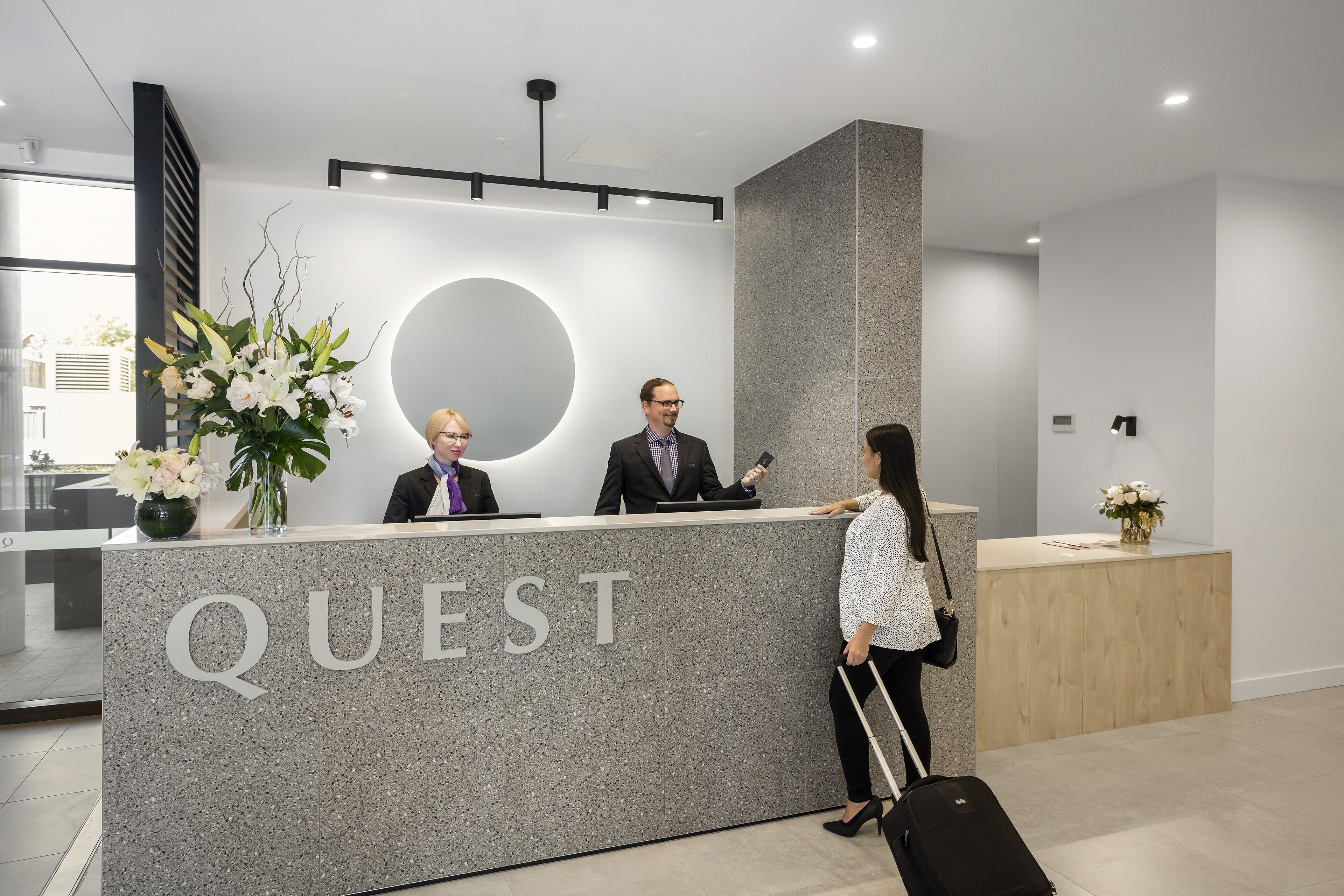 A modern reception desk with the word "QUEST" prominently displayed.