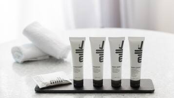 Four toiletry tubes on a tray with a rolled towel in the background.