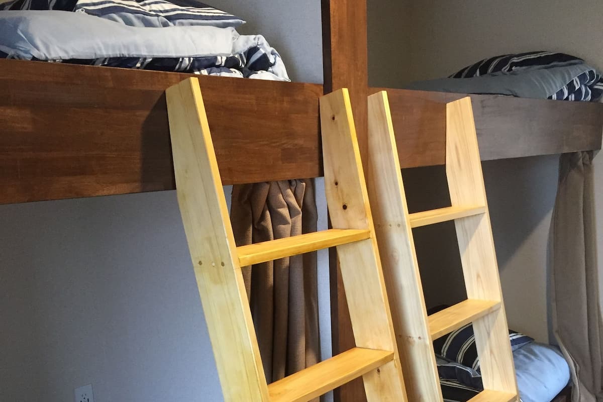 A bunk bed with a wooden ladder and two pillows on the lower bunk.