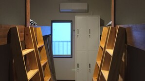 A room with wooden shelving units, a desk, a computer monitor, and a set of lockers. - Heart Hostel and Diner (Ise)