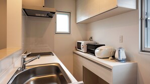 A compact kitchenette with a stainless steel sink, a microwave, a toaster, and a kettle. - Tsukasa Condo Chatan Araha (Chatan)