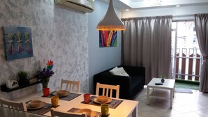 A dining area with a table set for two, a black sofa, and a small balcony with a view. - Couchbee at Perdana Exclusive Condominium (Petaling Jaya)