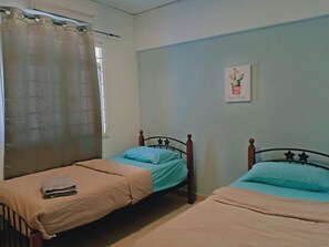 A bedroom with two single beds, a window with a curtain, and a wall-mounted picture. - Couchbee at Perdana Exclusive Condominium (Petaling Jaya)
