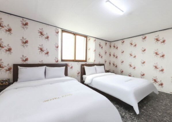 A hotel room with two single beds, floral wallpaper, a window, and a ceiling light. - Gunsan King Motel (Gunsan)