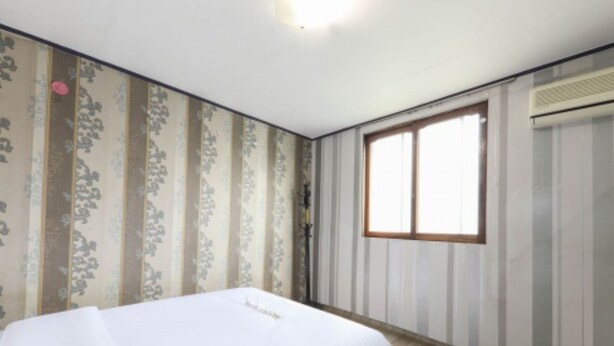 A room with a bed, a window, and striped wallpaper. - Gunsan King Motel (Gunsan)