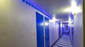A hotel hallway with blue doors, checkered floor, and blue LED strip lighting. - Gunsan King Motel (Gunsan)