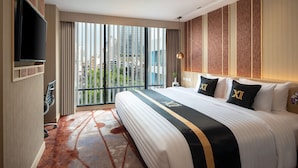 Een hotelkamer met een groot bed, een aan de muur bevestigde televisie en uitzicht op hoge gebouwen.