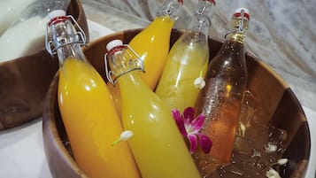 A wooden bowl containing several bottles of beverages, some with flowers.