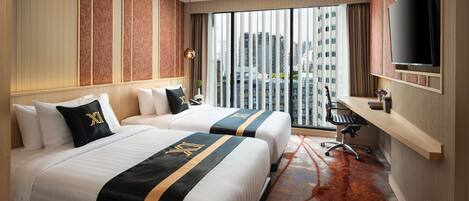 A hotel room with two beds, a desk, a TV, and a large window with a city view.