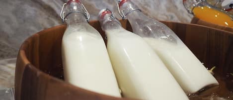 Three glass bottles with metal caps in a wooden bowl.
