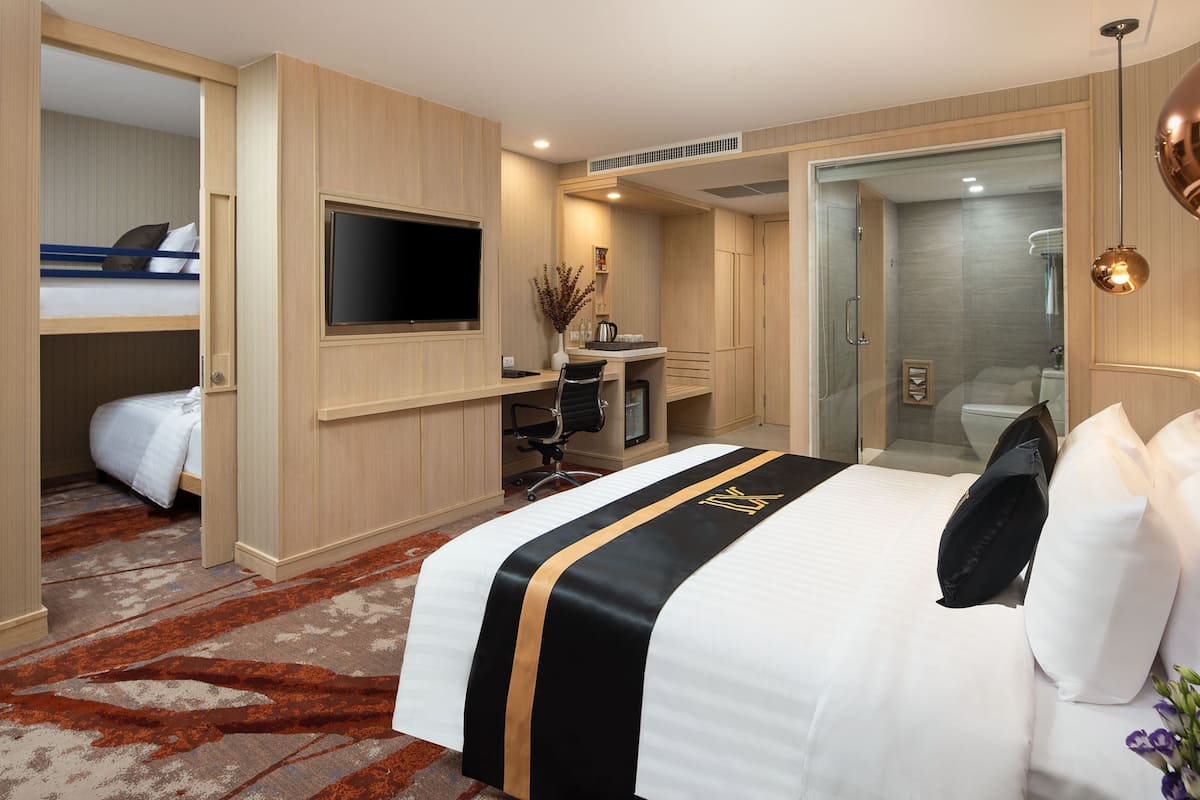 A hotel room with a bed, a desk, a TV, a shower, and a bathroom.