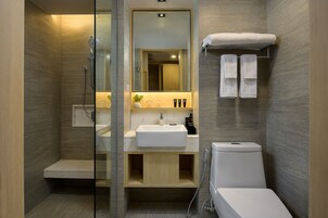 Un baño moderno con cabina de ducha de vidrio, un lavabo con espejo y un inodoro.