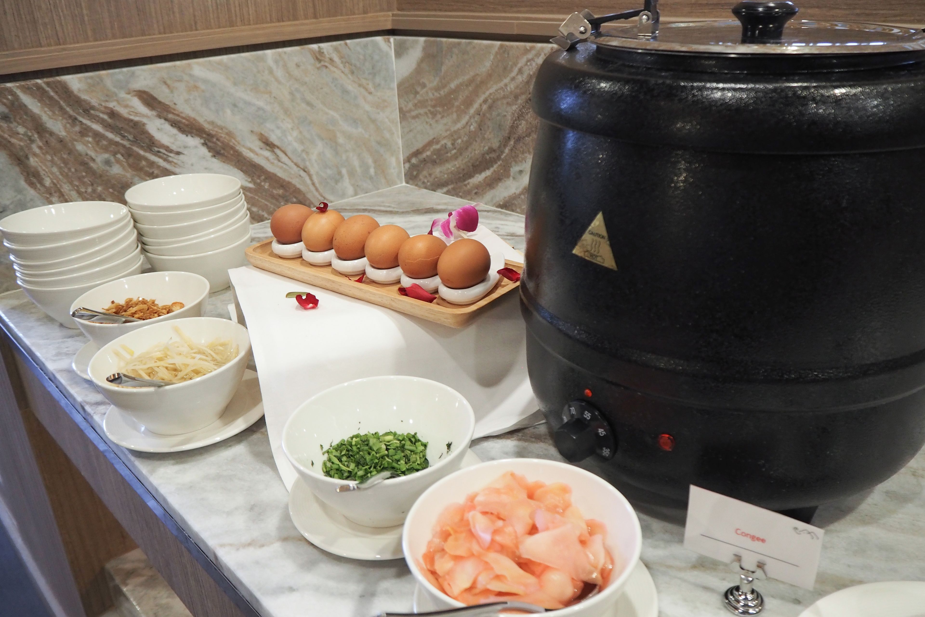 Montaje de bufé con diversos alimentos y una olla negra grande.