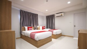 A modern hotel room with two beds, grey curtains, an air conditioning unit, and a white door. - Super OYO 483 Pannee Hotel Khaosan (Bangkok)