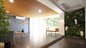 A modern reception area with a wooden ceiling, a green wall with plants, a seating area, and a small table with a plant. - Super OYO 483 Pannee Hotel Khaosan (Bangkok)
