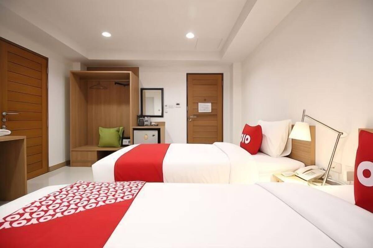 Une chambre d’hôtel avec un lit, un bureau, une armoire et un miroir.