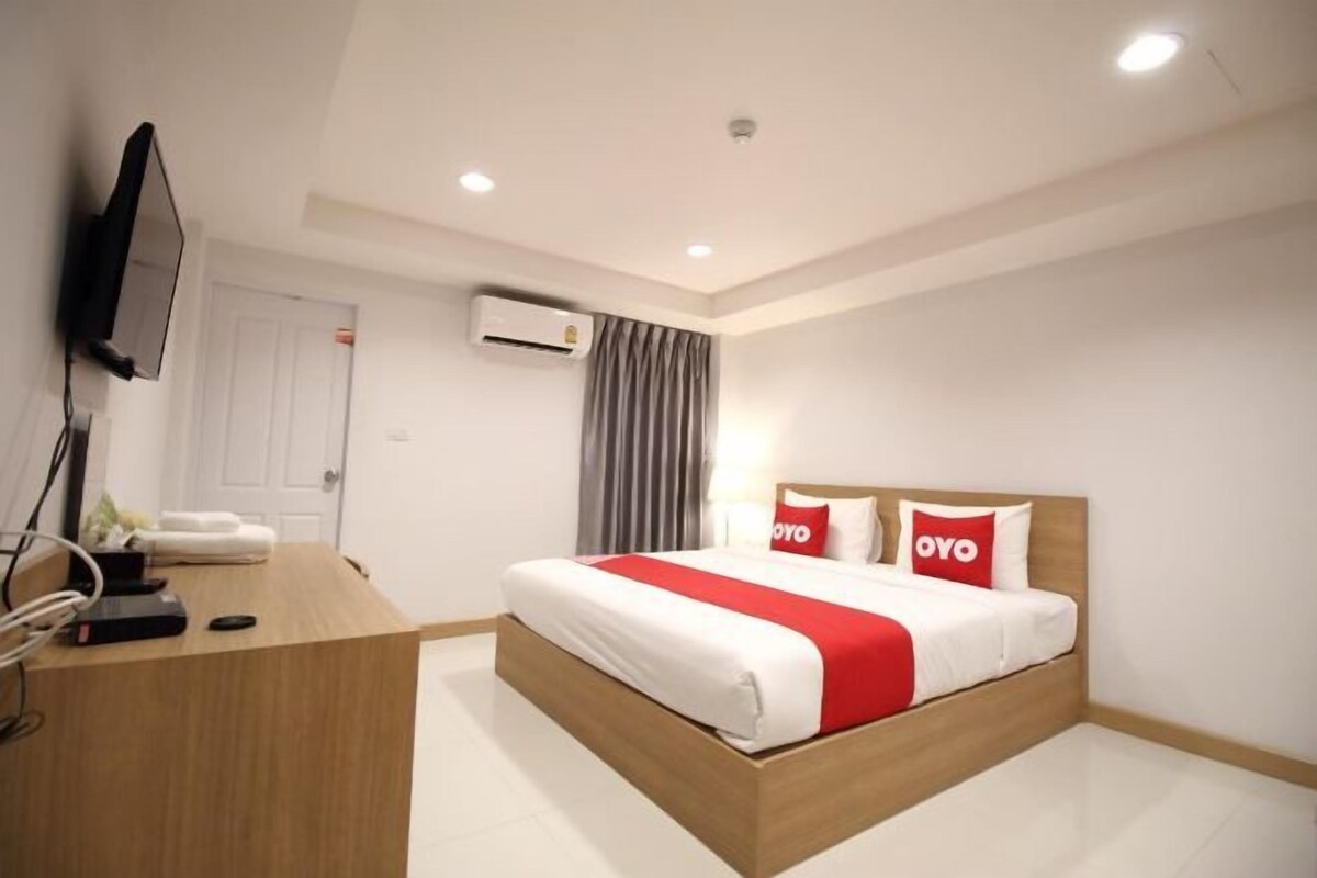 Una habitación de hotel con cama, escritorio, televisor y aire acondicionado.