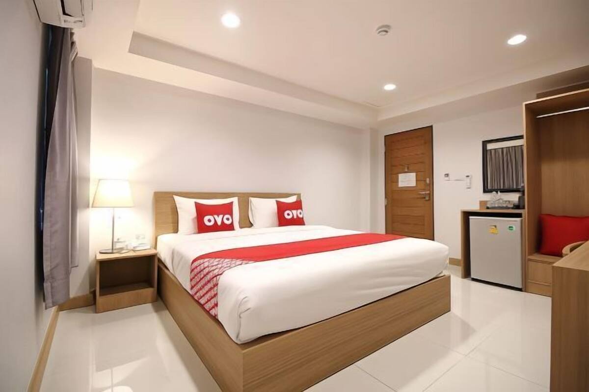 Une chambre d’hôtel équipée d’un lit, d’une table de chevet, d’une lampe, d’une armoire et d’un petit réfrigérateur.