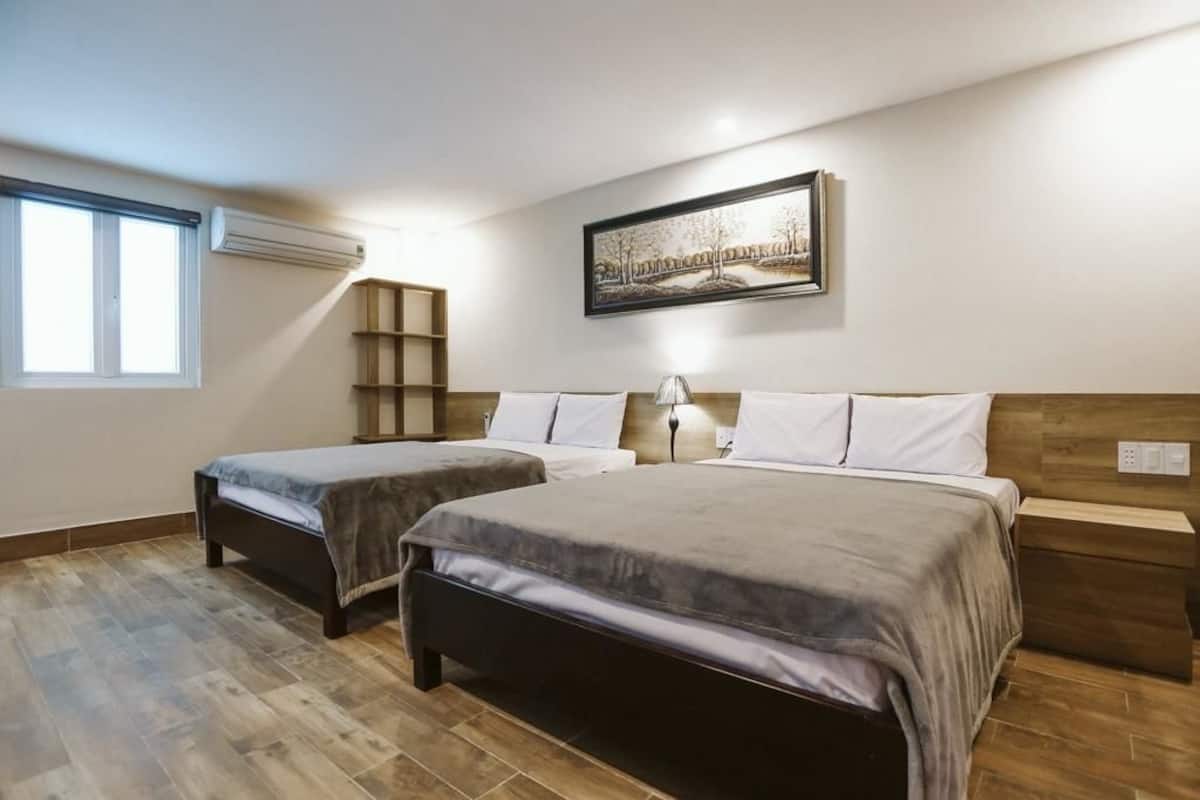 A bedroom with two beds, a window, an air conditioning unit, a wooden shelf, and a framed picture on the wall.