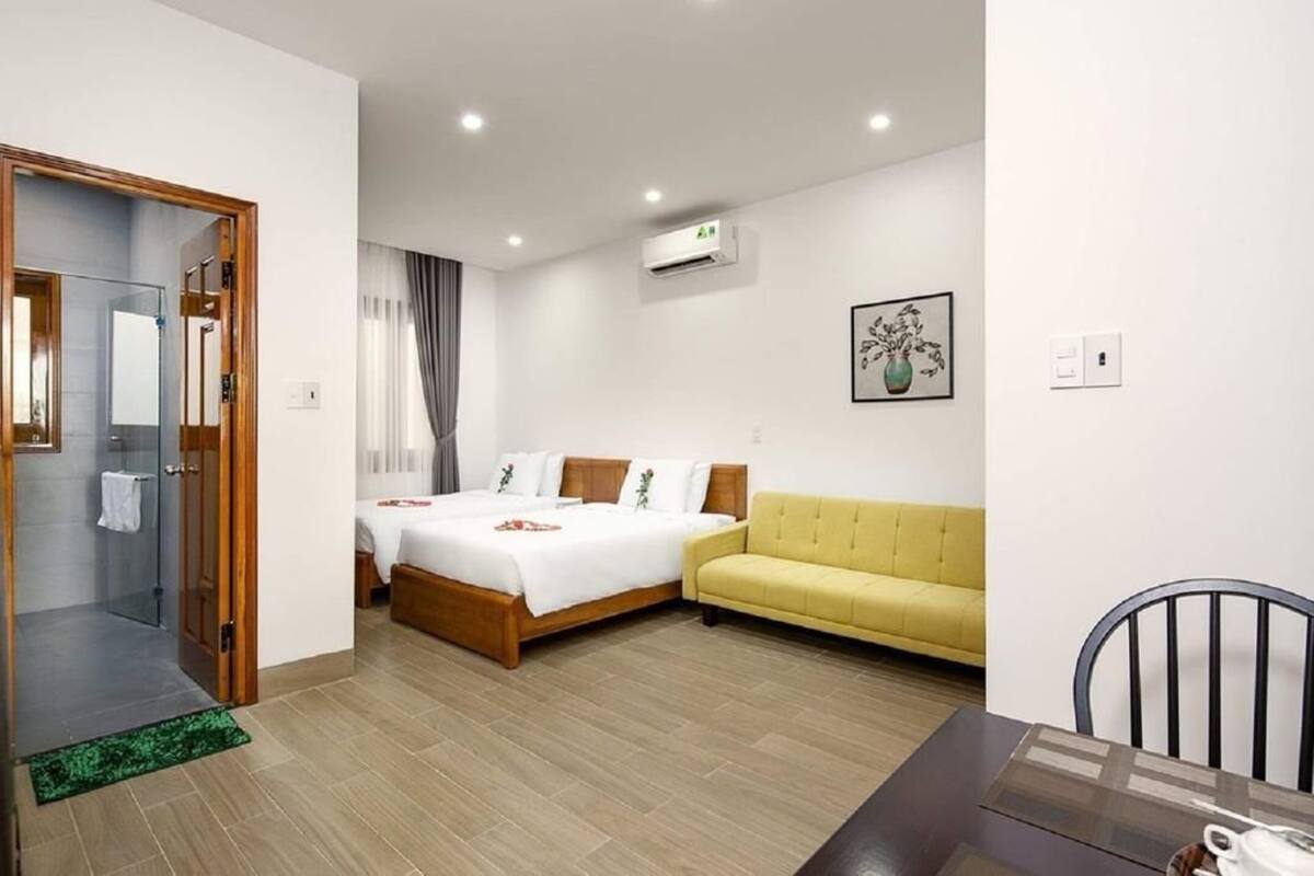A hotel room with a bed, a sofa, a dining table, and a shower area.