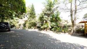 A paved driveway leading to a house with a yellow structure on the right. - OYO 927 Carina Hotel (Pacet)
