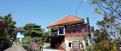 A two-story building with a red-tiled roof, a balcony, and a sign indicating it is a hotel.
