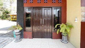 A building entrance with a double door, potted plants, and a small window. - OYO 927 Carina Hotel (Pacet)