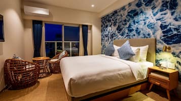 Un dormitorio con una cama grande, sillas de mimbre, una mesita de noche y un mural en la pared.