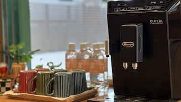 Una cafetera con una etiqueta que dice 'CAFÉ CALIENTE', el logotipo de De'Longhi y una vaporera de leche.