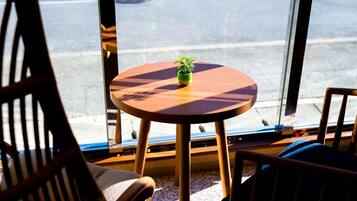 Una mesa redonda de madera con una pequeña planta en maceta, ubicada entre dos sillas de madera con cojines de asiento trenzados.