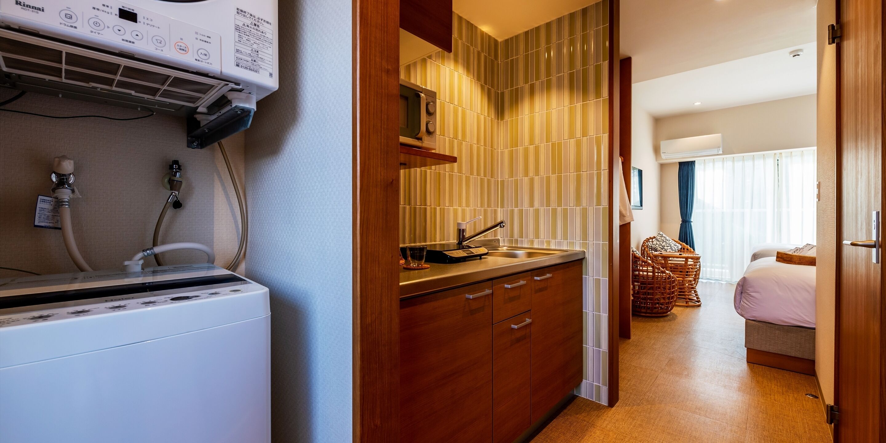 Una camera d'albergo compatta con angolo cottura, lavatrice e un letto.