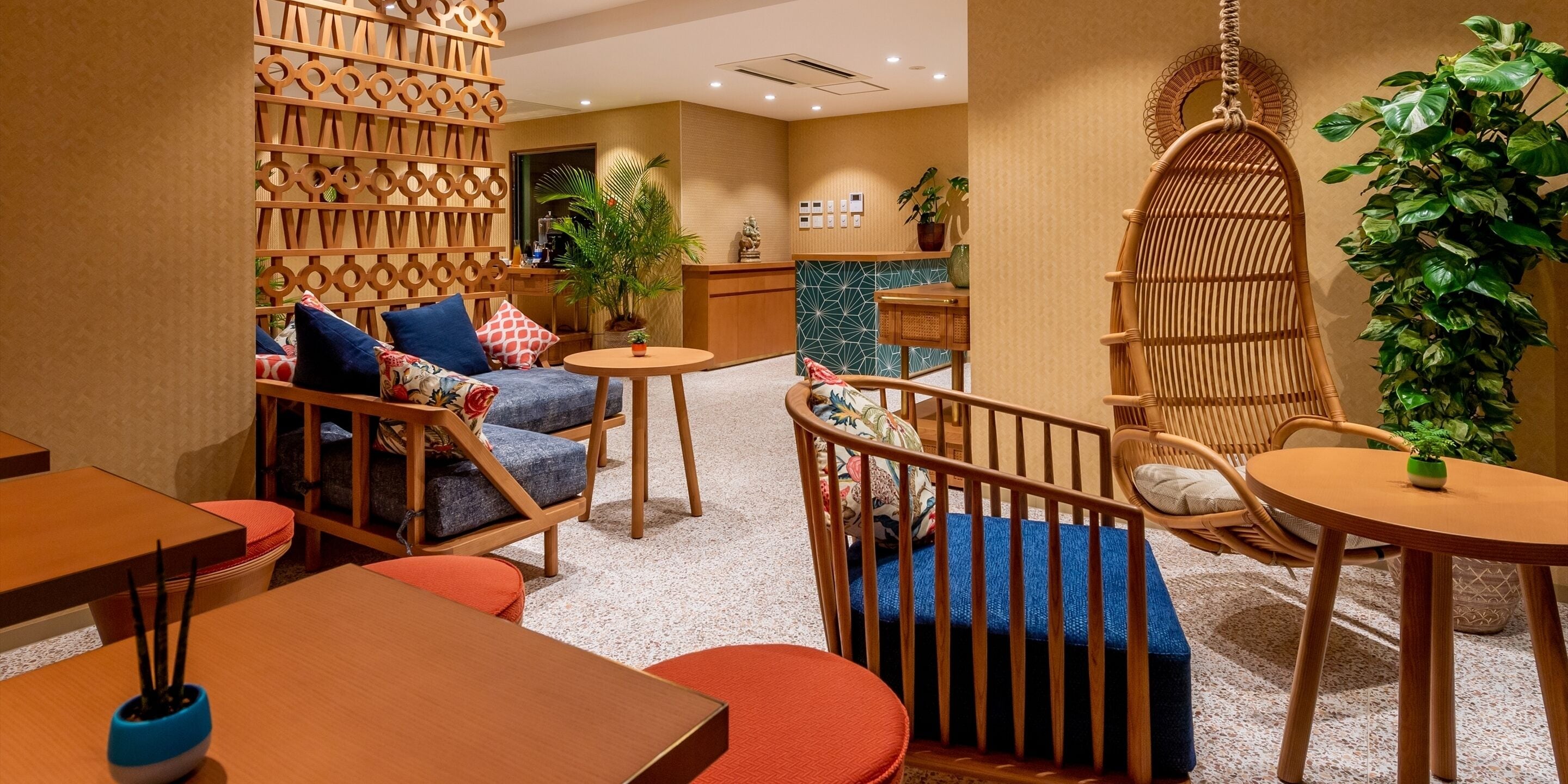 Eine moderne Hotelhalle mit Rezeption, einer Sitzecke mit Sofas und Sesseln sowie Zierpflanzen.