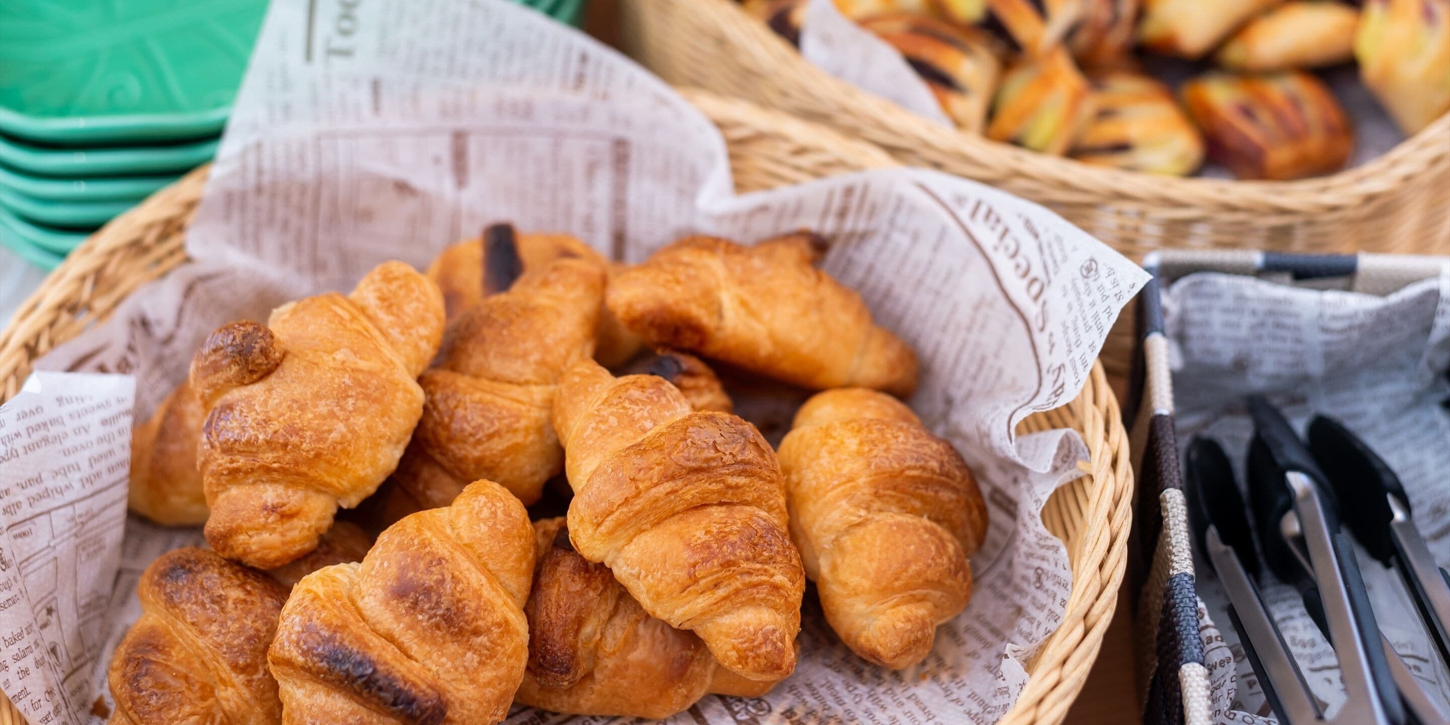 A basket of croissants on newspaper lining.