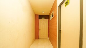 Un couloir étroit, dont le sol est recouvert de carreaux, mène à une porte portant le numéro 27.