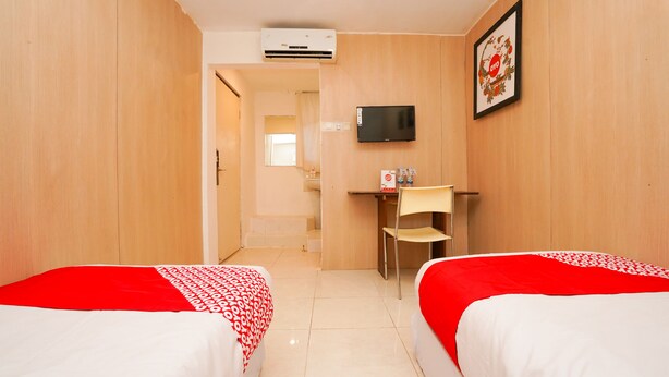 Une chambre d’hôtel avec deux lits, un bureau, une chaise, un téléviseur et un appareil de climatisation.