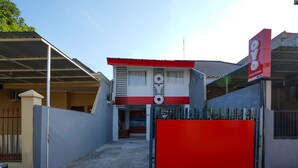 Un bâtiment à la façade rouge et blanche, doté d’une entrée fermée par un portail et d’une enseigne.