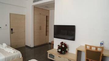 Una habitación de hotel con cama, escritorio, televisor, armario y baño.