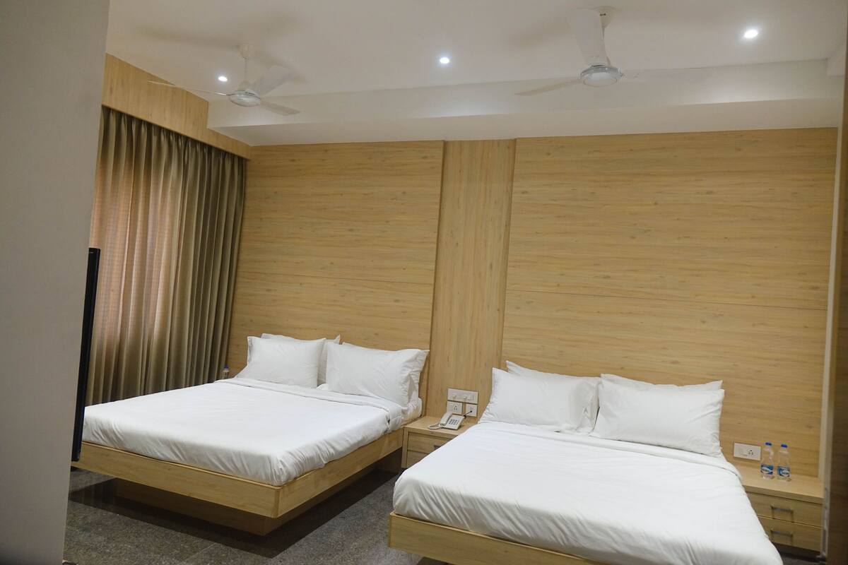 A hotel room with two wooden beds, a telephone, and a nightstand with water bottles.