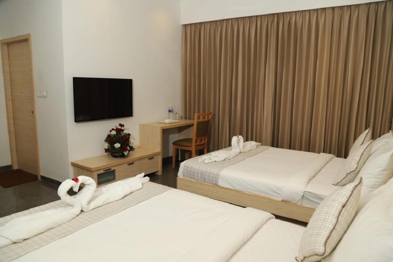 Una habitación de hotel con dos camas, un escritorio, una silla, un televisor y una cortina.