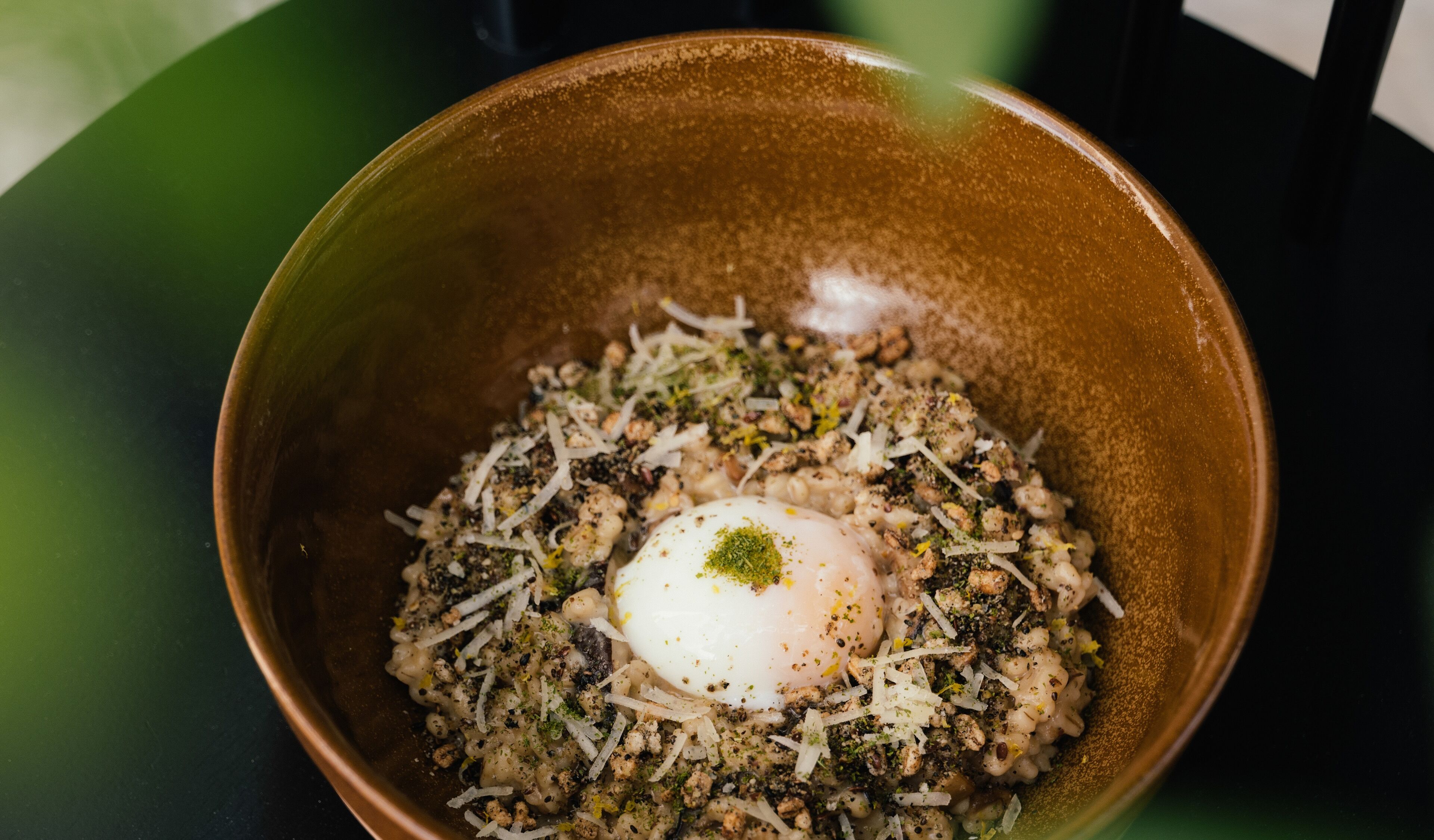 A bowl of food with a poached egg on top, surrounded by a mixture of grains and herbs.