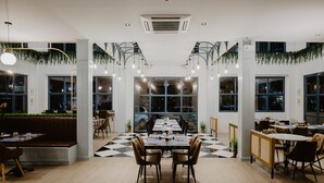 En rymlig restaurang med högt i tak, stora fönster och ett rutmönstrat golv.