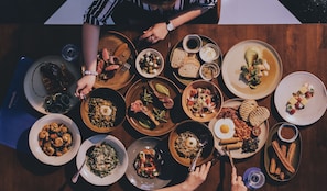 A table with various dishes and a person reaching for a plate.