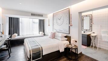 Una habitación de hotel moderna con una cama grande, un escritorio y un baño.
