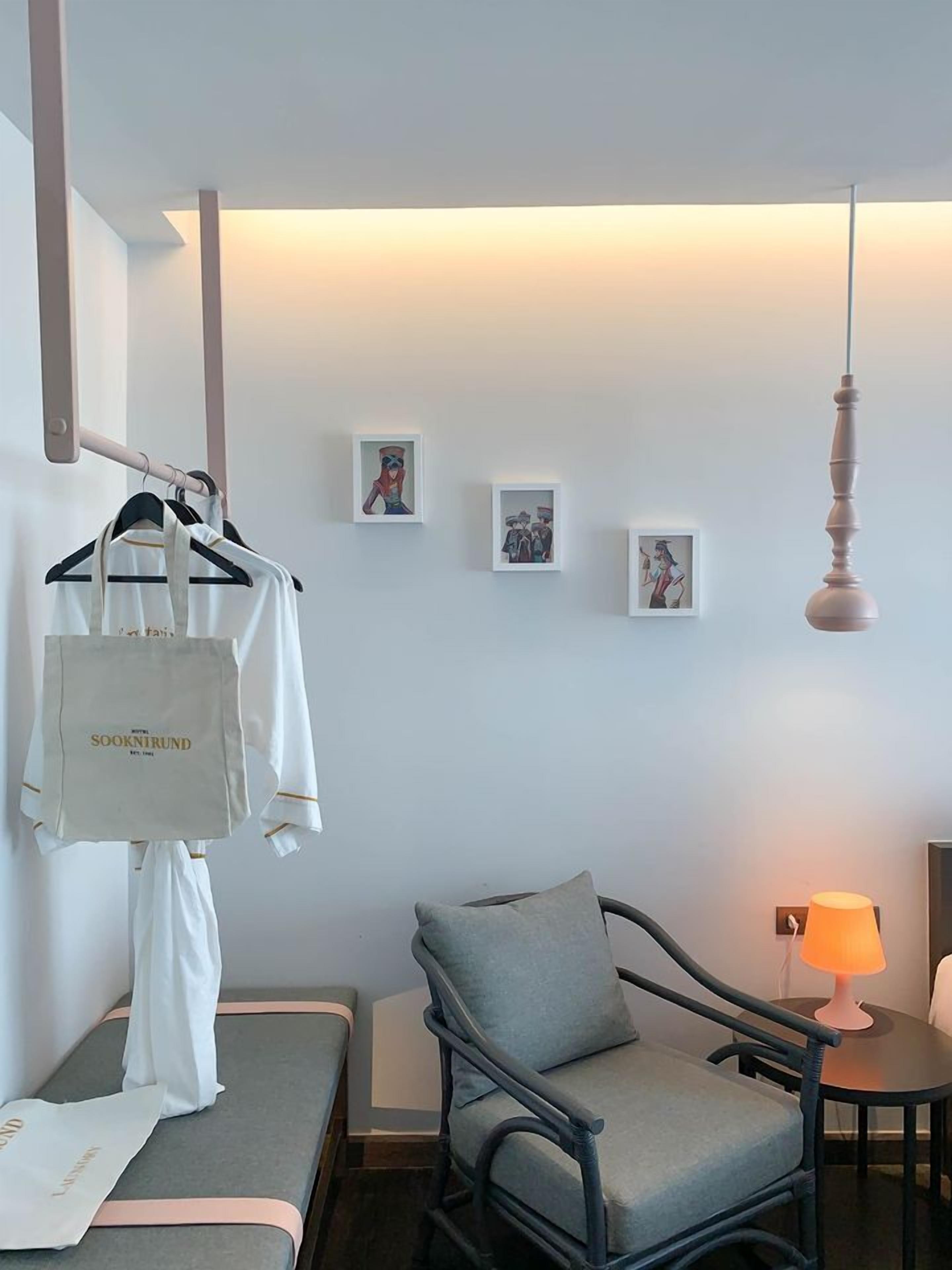 Una habitación de hotel con una cama, una silla, una mesa con lámpara y decoración en la pared.