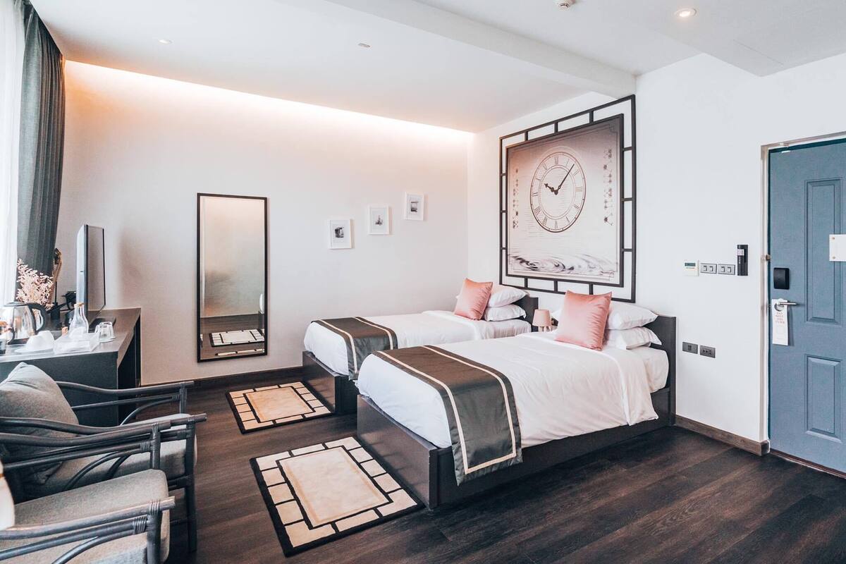 A modern hotel room with a large bed, two bedside tables, a desk, and a chair.