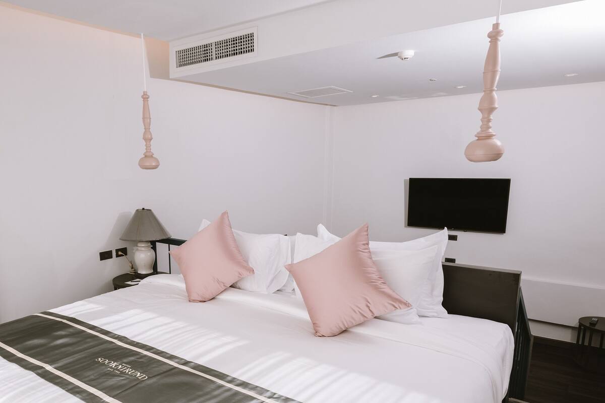 A hotel room with a bed, a TV, a lamp, and a picture on the wall.