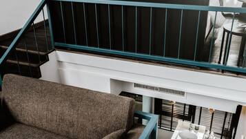 Un intérieur moderne avec un escalier menant à une chambre en mezzanine, un canapé et une petite table avec un évier.