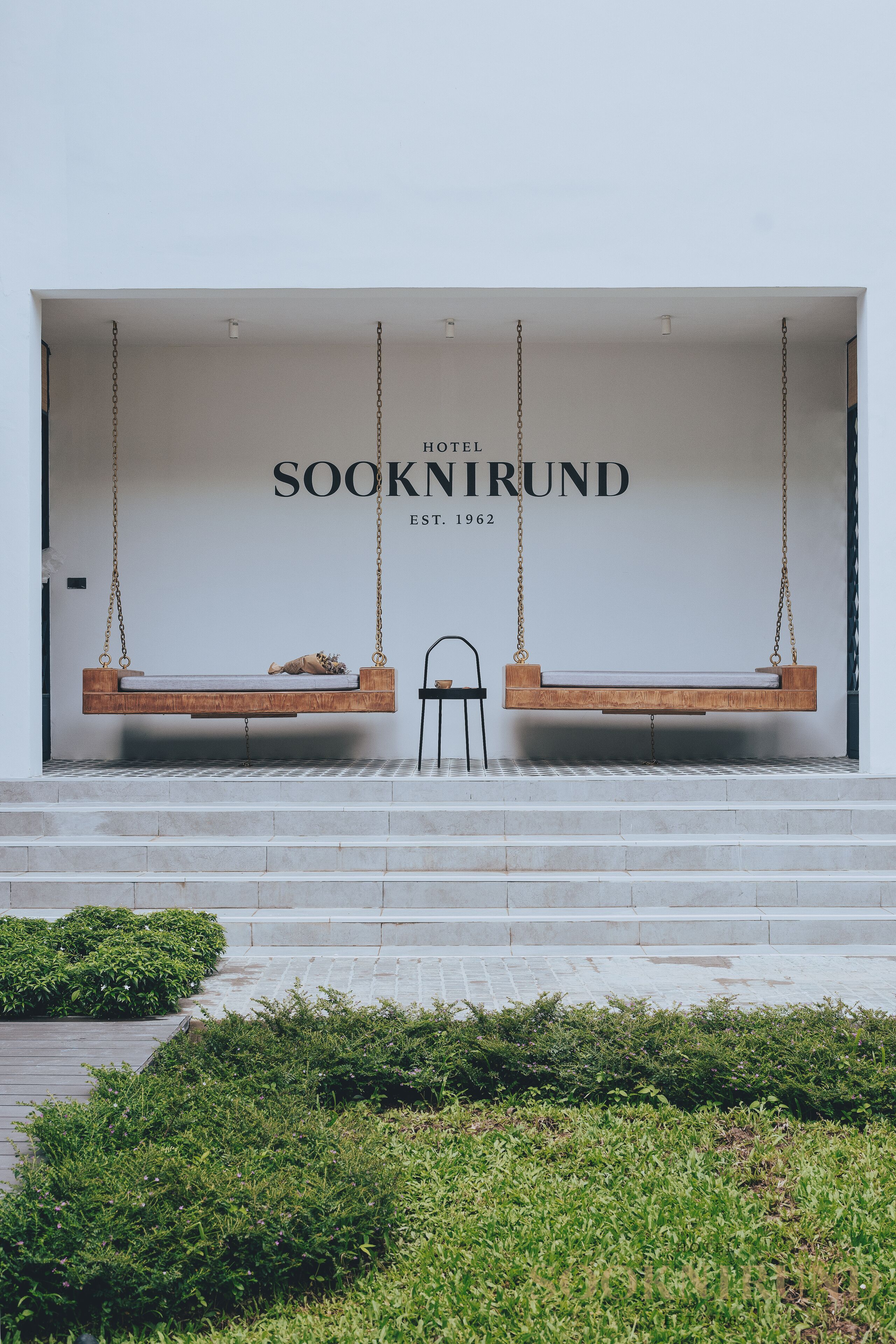 A hotel entrance with a swing seating area and a chair.