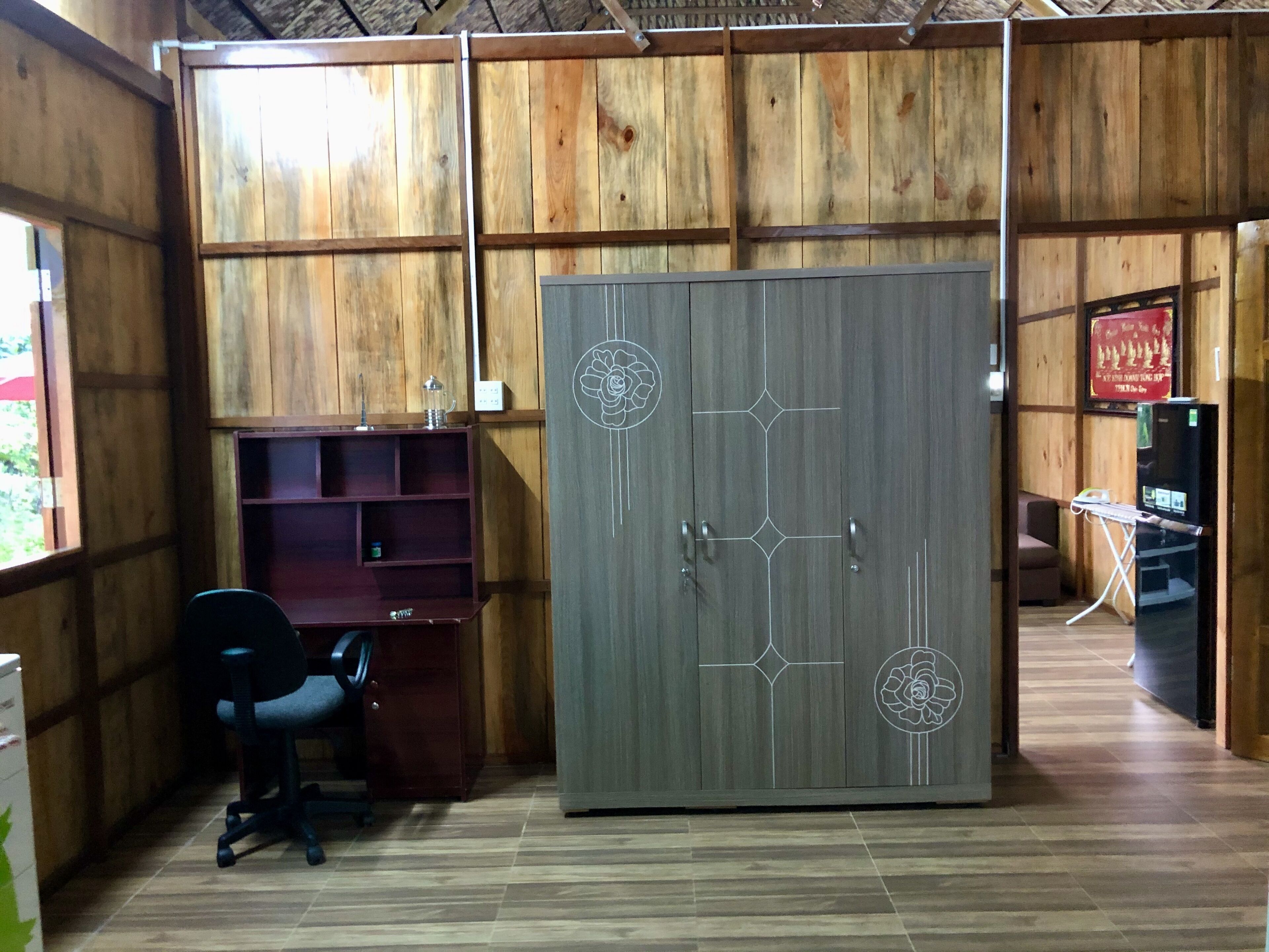 Une pièce comprenant une armoire en bois, un bureau avec une chaise et une petite étagère.